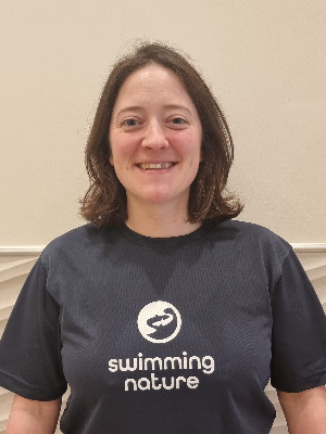 Head‑and‑shoulders portrait of swimming instructor Frankie in a Swimming Nature T‑shirt, smiling.