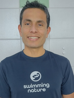 Head‑and‑shoulders portrait of swimming instructor Luis Guillermo in a Swimming Nature T‑shirt, smiling.