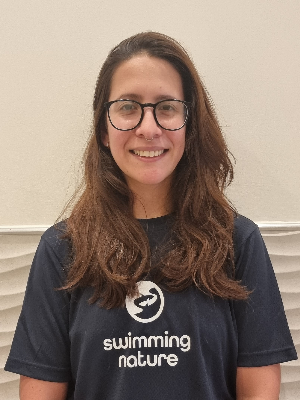 Head‑and‑shoulders portrait of swimming instructor Maria in a Swimming Nature T‑shirt, smiling.