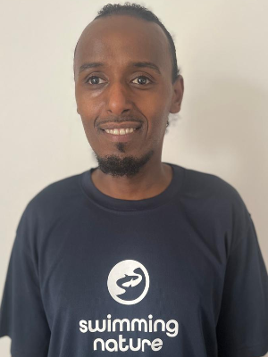 Head‑and‑shoulders portrait of swimming instructor Joseph in a Swimming Nature T‑shirt, smiling.