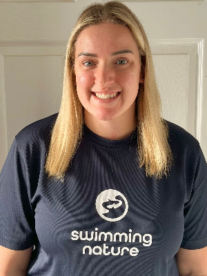 Head‑and‑shoulders portrait of swimming instructor Amanda in a Swimming Nature T‑shirt, smiling.