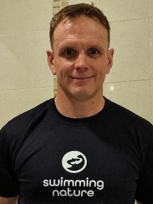 Head‑and‑shoulders portrait of swimming instructor Ioan in a Swimming Nature T‑shirt, smiling.