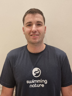 Head‑and‑shoulders portrait of swimming instructor Alejandro in a Swimming Nature T‑shirt, smiling.