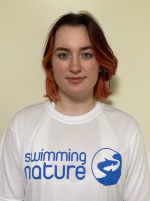 Head‑and‑shoulders portrait of swimming instructor Sophie in a Swimming Nature T‑shirt, smiling.