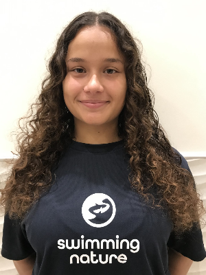 Head‑and‑shoulders portrait of swimming instructor Alicia in a Swimming Nature T‑shirt, smiling.