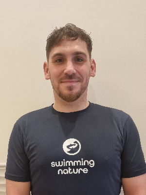 Head‑and‑shoulders portrait of swimming instructor Thomas in a Swimming Nature T‑shirt, smiling.