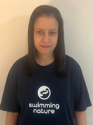 Head‑and‑shoulders portrait of swimming instructor Nadia in a Swimming Nature T‑shirt, smiling.
