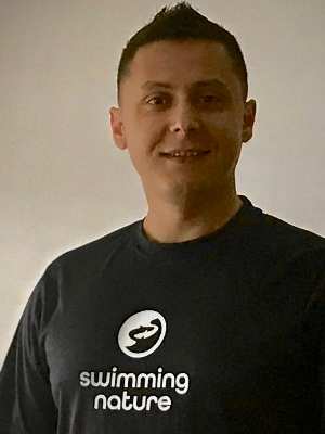 Head‑and‑shoulders portrait of swimming instructor Erald in a Swimming Nature T‑shirt, smiling.