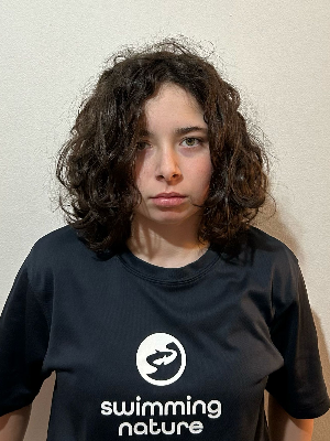 Head‑and‑shoulders portrait of swimming instructor Aisha in a Swimming Nature T‑shirt, smiling.