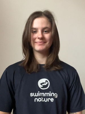 Head‑and‑shoulders portrait of swimming instructor Claudia in a Swimming Nature T‑shirt, smiling.