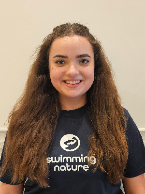 Head‑and‑shoulders portrait of swimming instructor Natalie in a Swimming Nature T‑shirt, smiling.