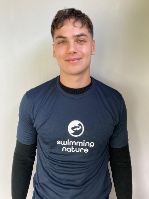 Head‑and‑shoulders portrait of swimming instructor Matthew in a Swimming Nature T‑shirt, smiling.