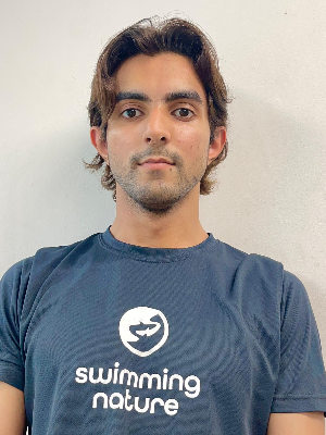 Head‑and‑shoulders portrait of swimming instructor Shaheer in a Swimming Nature T‑shirt, smiling.