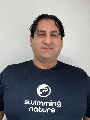 Head‑and‑shoulders portrait of swimming instructor Roberto in a Swimming Nature T‑shirt, smiling.