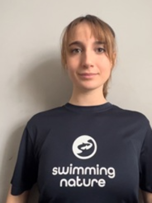 Head‑and‑shoulders portrait of swimming instructor Sara in a Swimming Nature T‑shirt, smiling.