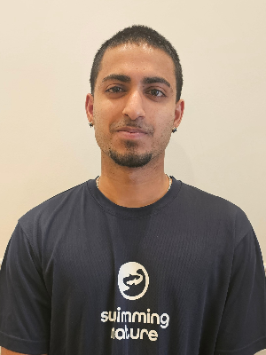 Head‑and‑shoulders portrait of swimming instructor Sanuth in a Swimming Nature T‑shirt, smiling.