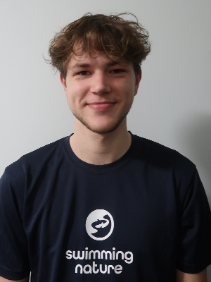 Head‑and‑shoulders portrait of swimming instructor Kristians in a Swimming Nature T‑shirt, smiling.
