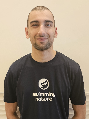 Head‑and‑shoulders portrait of swimming instructor Lawrence in a Swimming Nature T‑shirt, smiling.